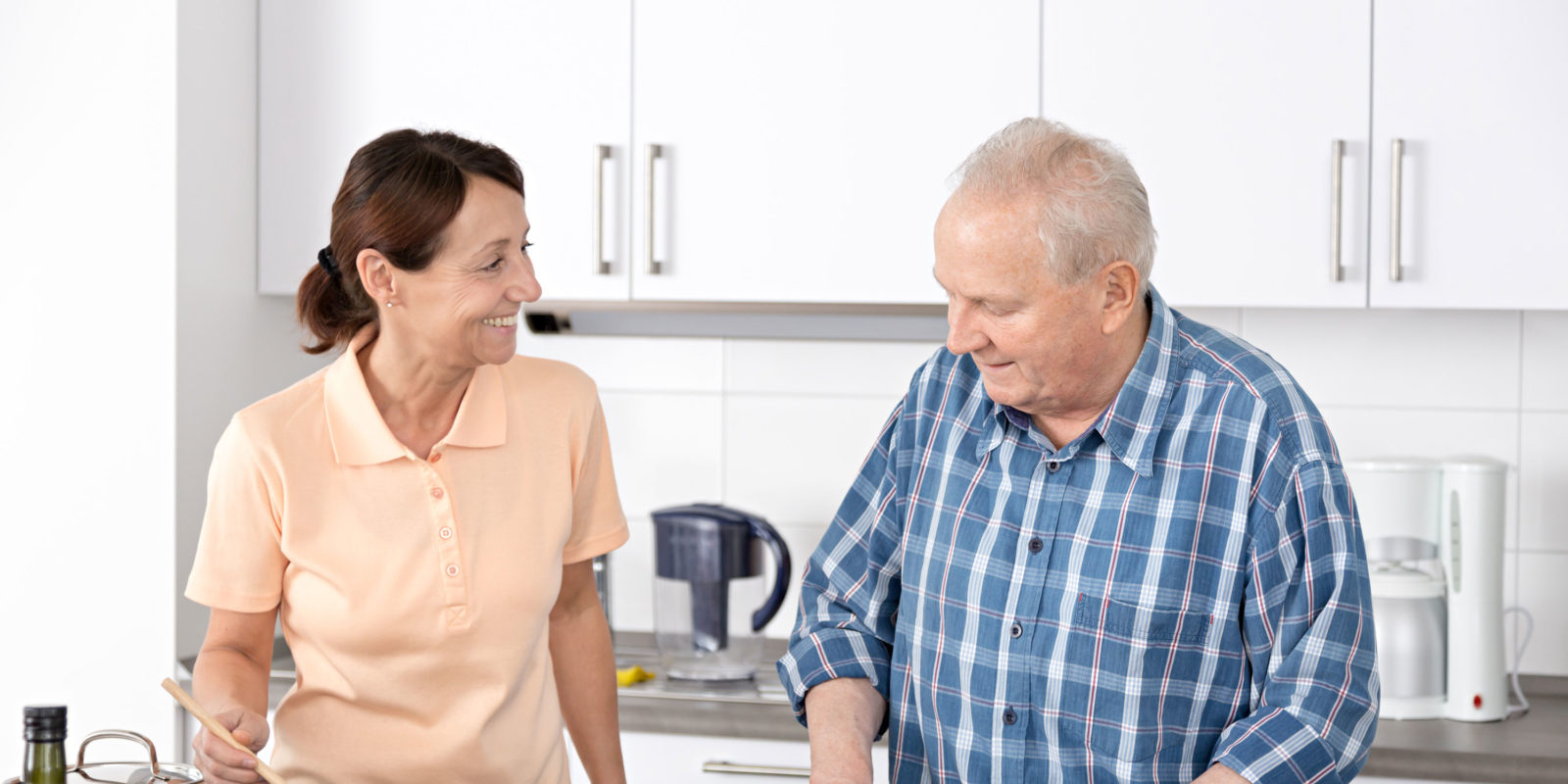 Home caregiver with senior man in a kitchen