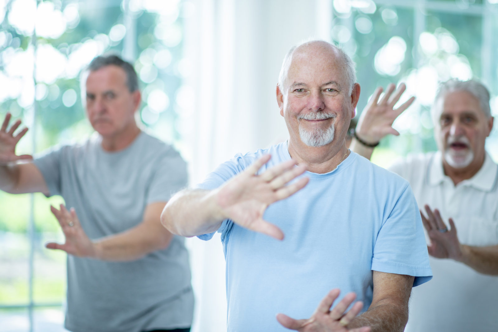 group of senior men are doing tai chi in a fitness center