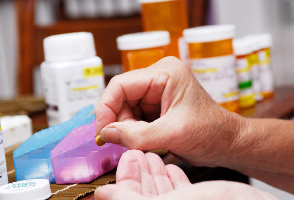 hand putting meds into pillbox