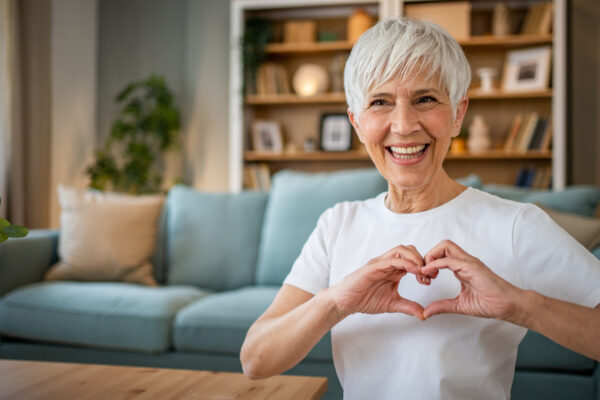 Happy elderly woman making a heart sign with her hands